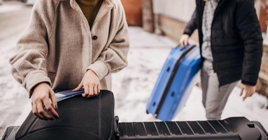 Couple unloading suitcases in the car trunk